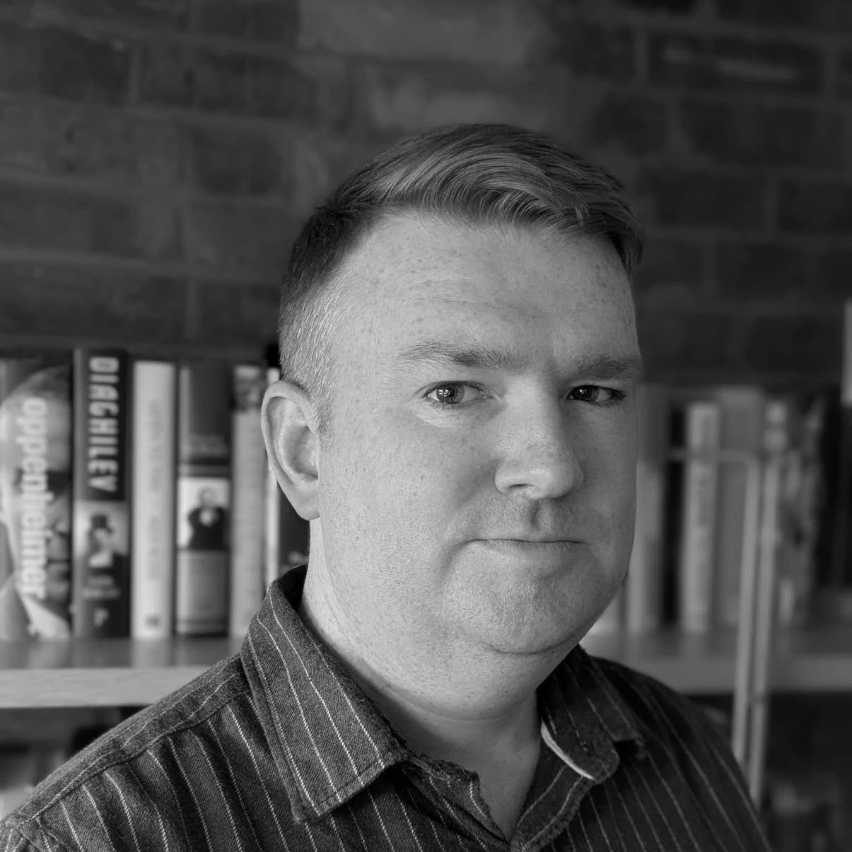 Black and white portrait of a man with a bookshelf in the background
